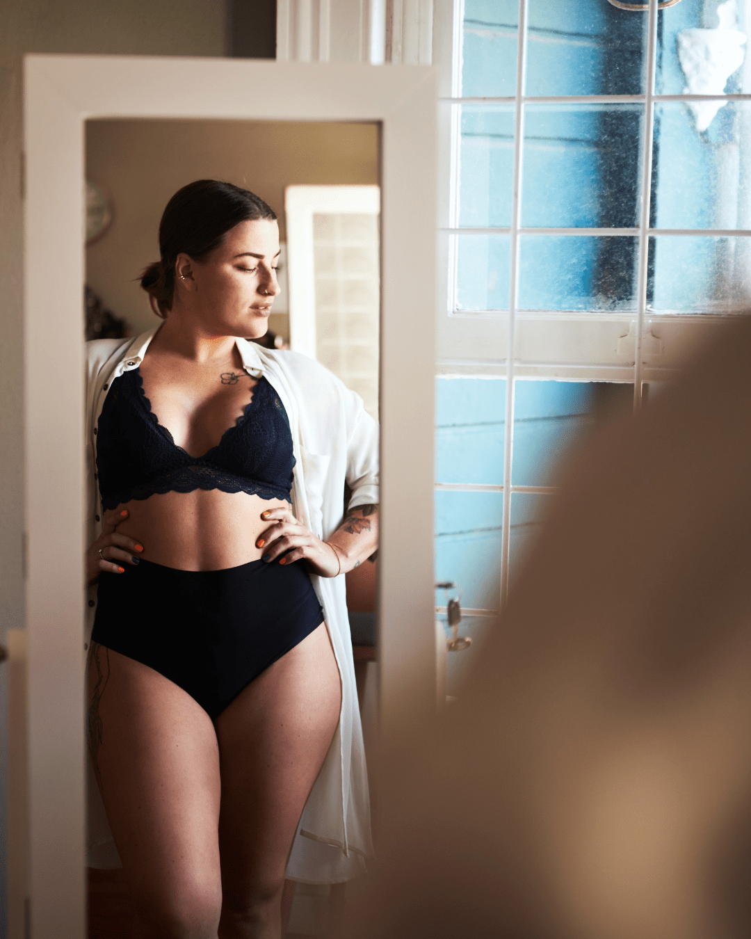 Une jeune femme en sous-vêtements estpleine de confiance en elle est face à son miroir, suite à un accompagnement sophrologie et sexualité.
